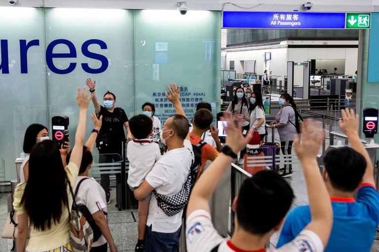 People waving goodbye as a family makes their way through the departure gates of Hong Kong's International Airport, July 22, 2021. Credit: AFP
