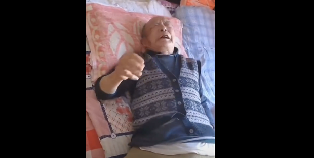 A 93-year-old man who was beaten up by police after he tried to get a PCR test certificate to attend a hospital appointment lies in bed explaining the incident to neighbors in the northeastern city of Dandong. The man later took his life. Credit: Citizen journalist.