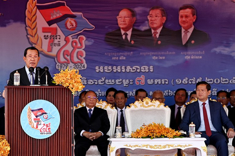 Cambodian People's Party President Hun Sen, left, addresses supporters in Phnom Penh as his son Prime Minister Hun Manet, right, listens during a ceremony marking the 45th anniversary of the fall of the Khmer Rouge regime, Jan. 7, 2024. (Tang Chhin Sothy/AFP)