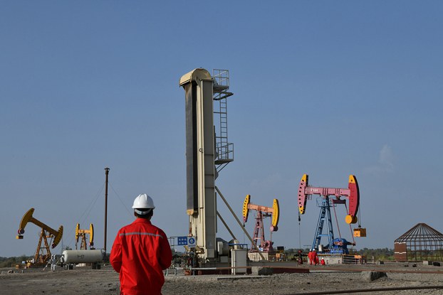 Workers are seen near pumpjacks at a China National Petroleum Corp oil field in Bayingol in northwestern China’s Xinjiang region, Aug. 7, 2019. (Reuters)