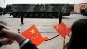 Spectators wave Chinese flags as military vehicles carrying DF-41 nuclear ballistic missiles roll during a parade to commemorate the 70th anniversary of the founding of Communist China in Beijing