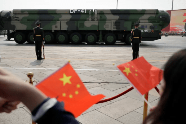 Spectators wave Chinese flags as military vehicles carrying DF-41 nuclear ballistic missiles roll during a parade to commemorate the 70th anniversary of the founding of Communist China in Beijing